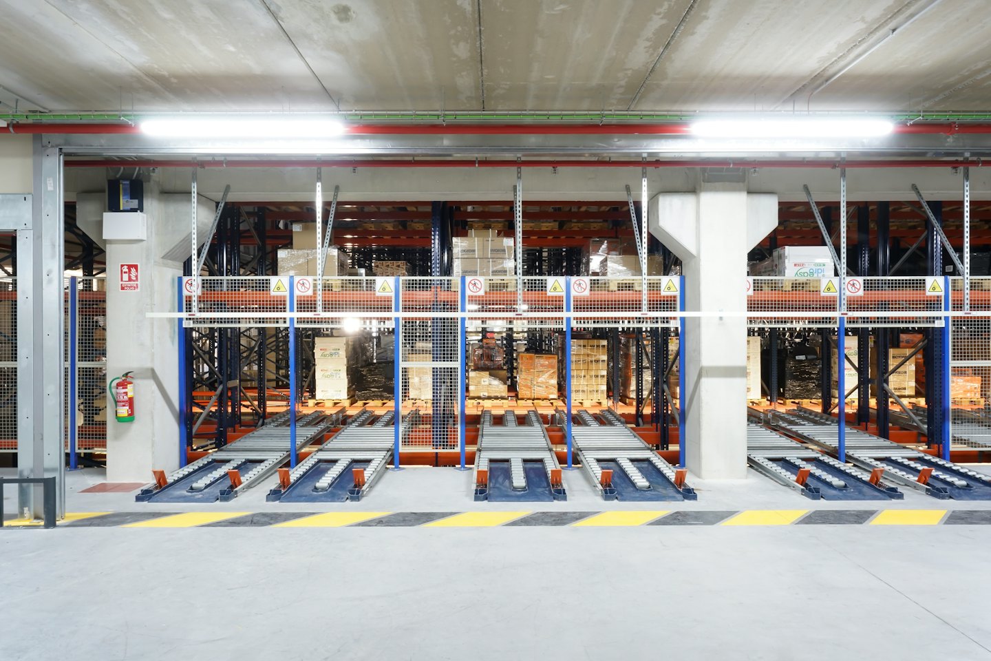 Almacén automatizado con estanterías de palets y sistemas de transporte.